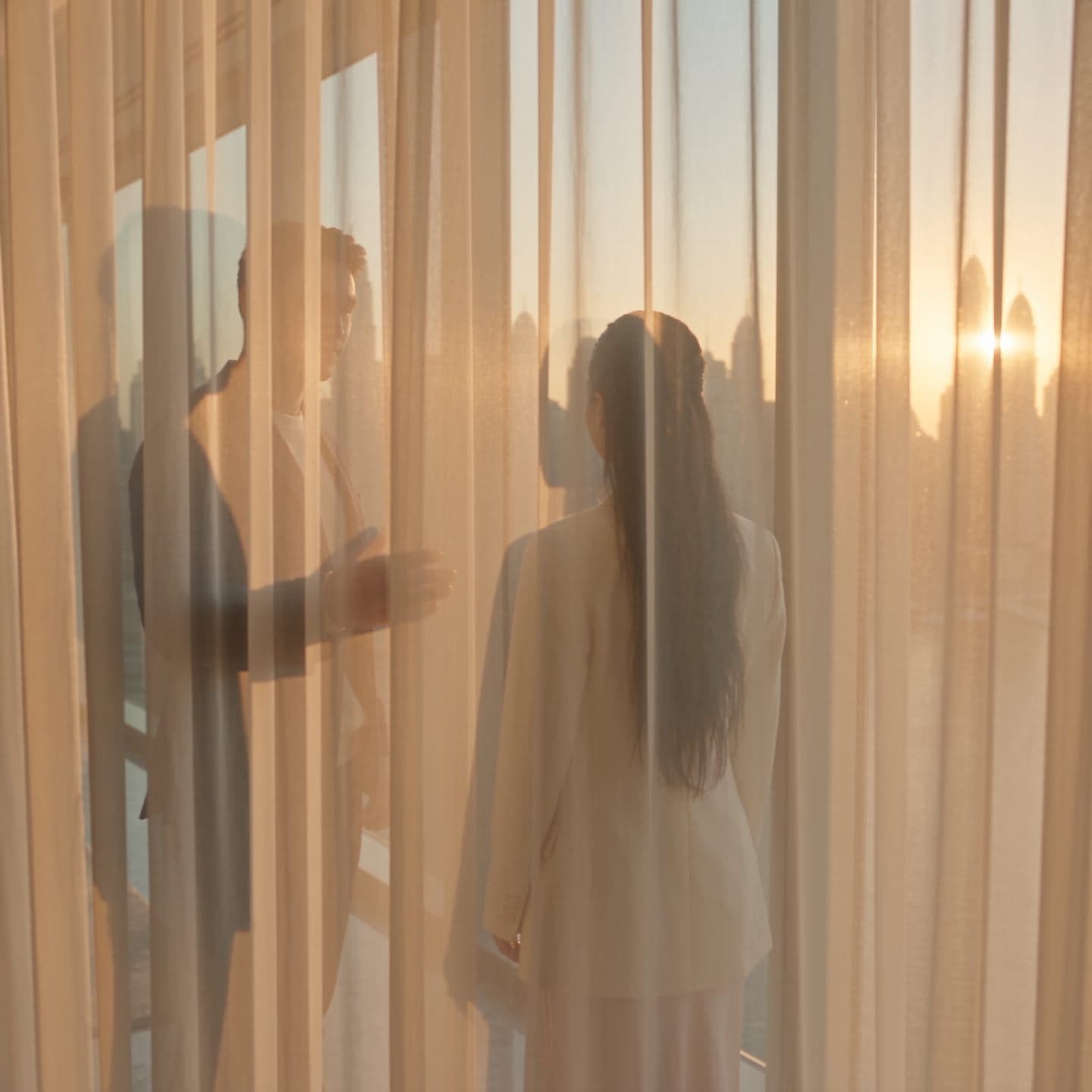 Two people by a window, looking out at the Dubai skyline.